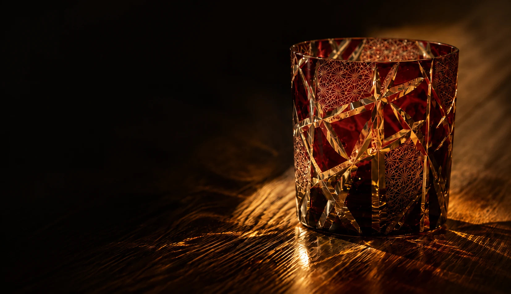 Deep Red Lightning Cut crystal glass in warm light on walnut